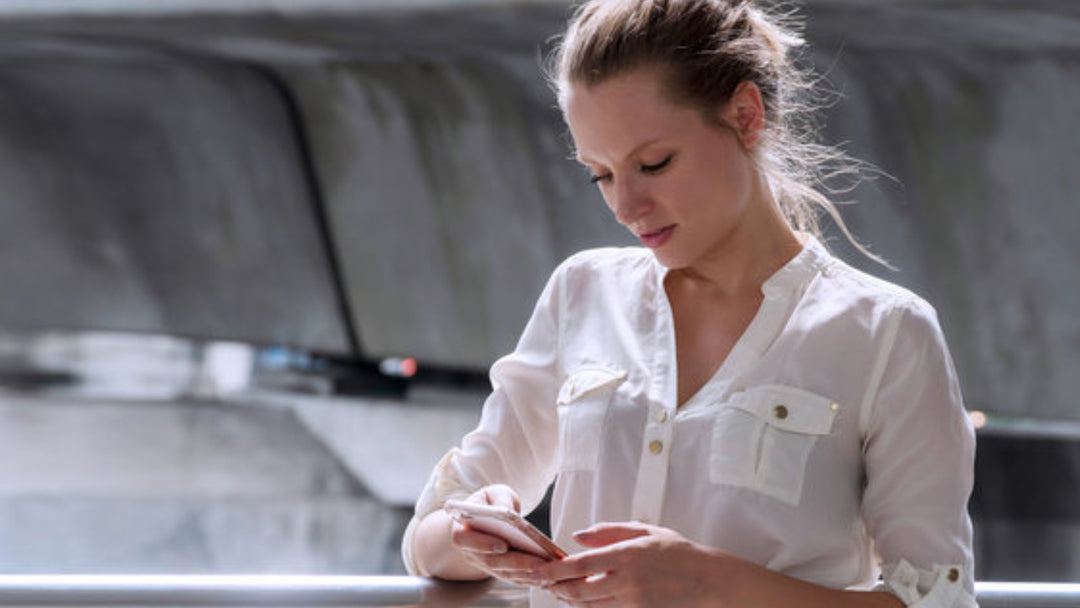 woman on an iPhone in white blouse