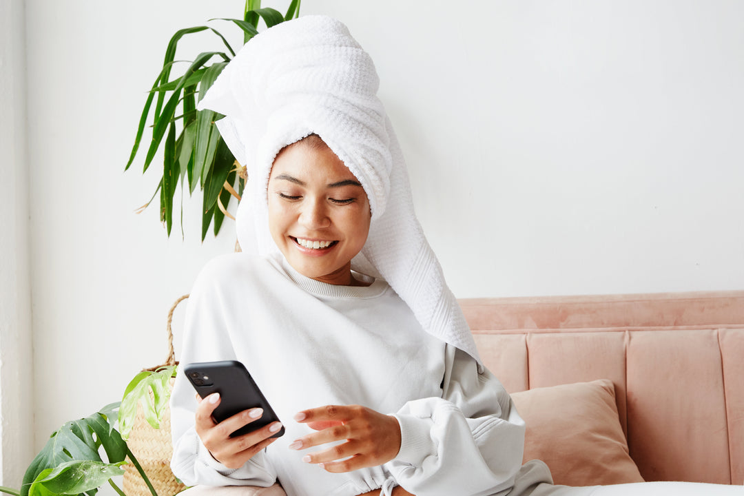 young woman on couch after shower with smartphone